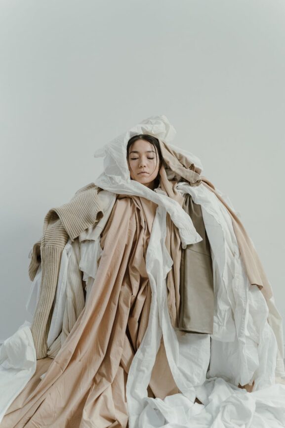 a woman cover with dumped clothes